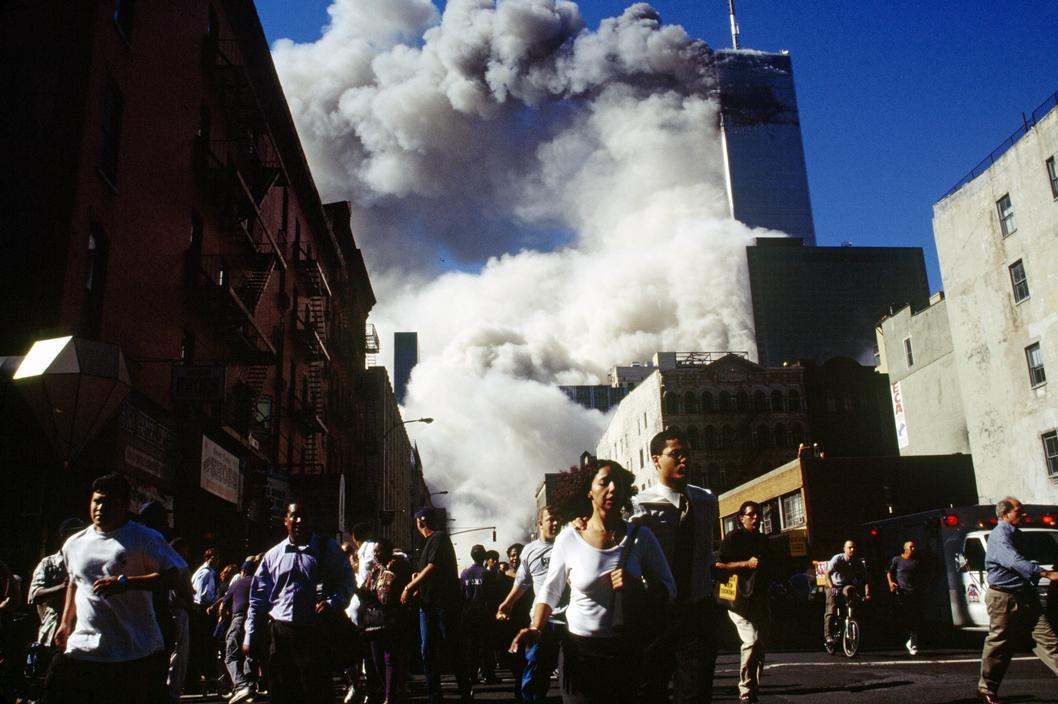 EE.UU. Ciudad de Nueva York. 11 de septiembre de 2001. Los peatones en Church Street huyen de los escombros que caen cuando la Torre 2, la Torre Sur, del World Trade Center se derrumba a las 9:55 am. La Torre 1, la Torre Norte, que aún está aquí, se derrumbó a las 10:29 am. El Seven World Trade Center, el edificio de 47 pisos visto inmediatamente frente a la Torre 1, se derrumbó a las 5:25 pm – foto de Susan Meiselas.